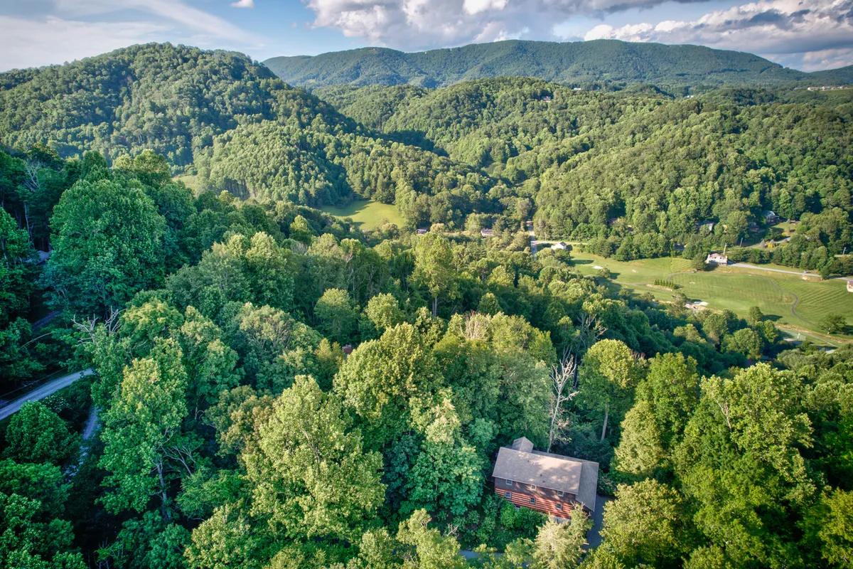 The hero image showcases a charming wooden log cabin nestled among lush green trees with a stunning mountain backdrop. The setting exudes tranquility and natural beauty, inviting guests to relax and connect with nature. The cabin's rustic exterior blends seamlessly with the surrounding landscape, and the expansive views hint at endless outdoor adventures.