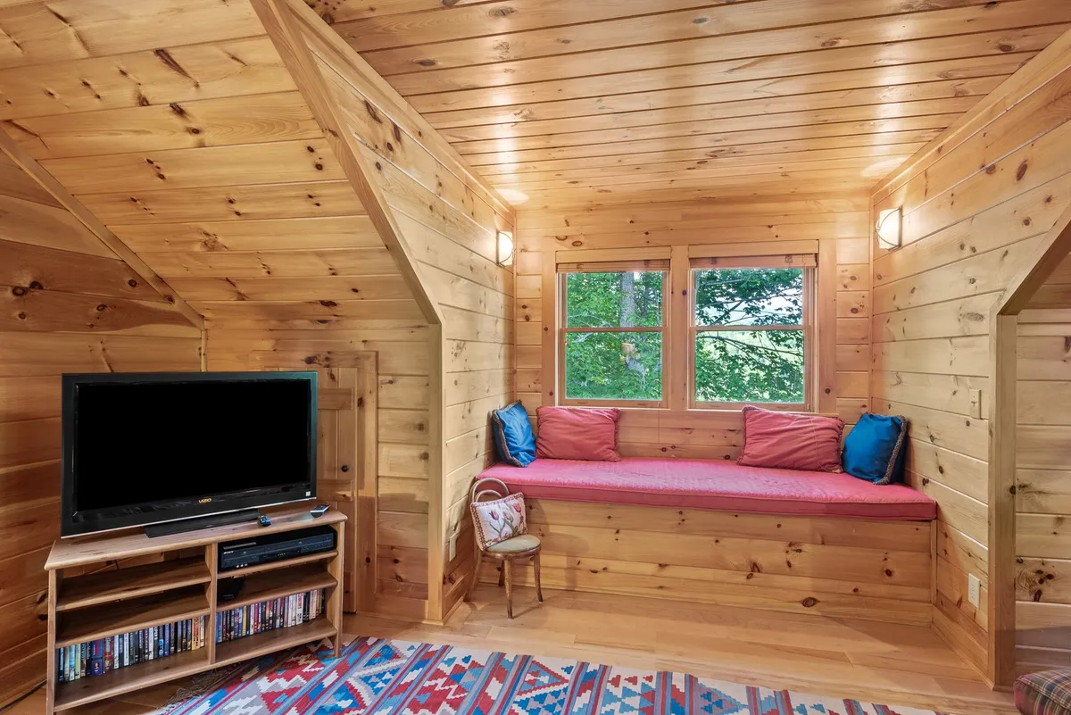 A cozy nook with wooden paneling, a cushioned window seat, and a TV stand. This space is ideal for curling up with a book or gathering for a movie, echoing the section's emphasis on relaxation and togetherness.